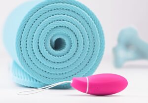 Pelvic floor Kegel exercise device next to rolled yoga mat – postpartum recovery tools for strengthening core and pelvic muscles